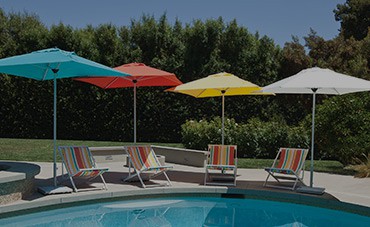 Four colorful umbrellas and chairs by pool