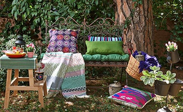 Cushions and fabrics on a bench under a tree