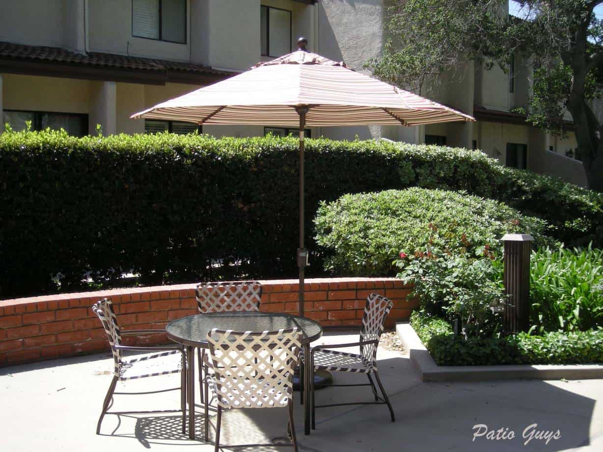 outdoor acrylic dining table and chair with a stripped umbrella in apartment complex